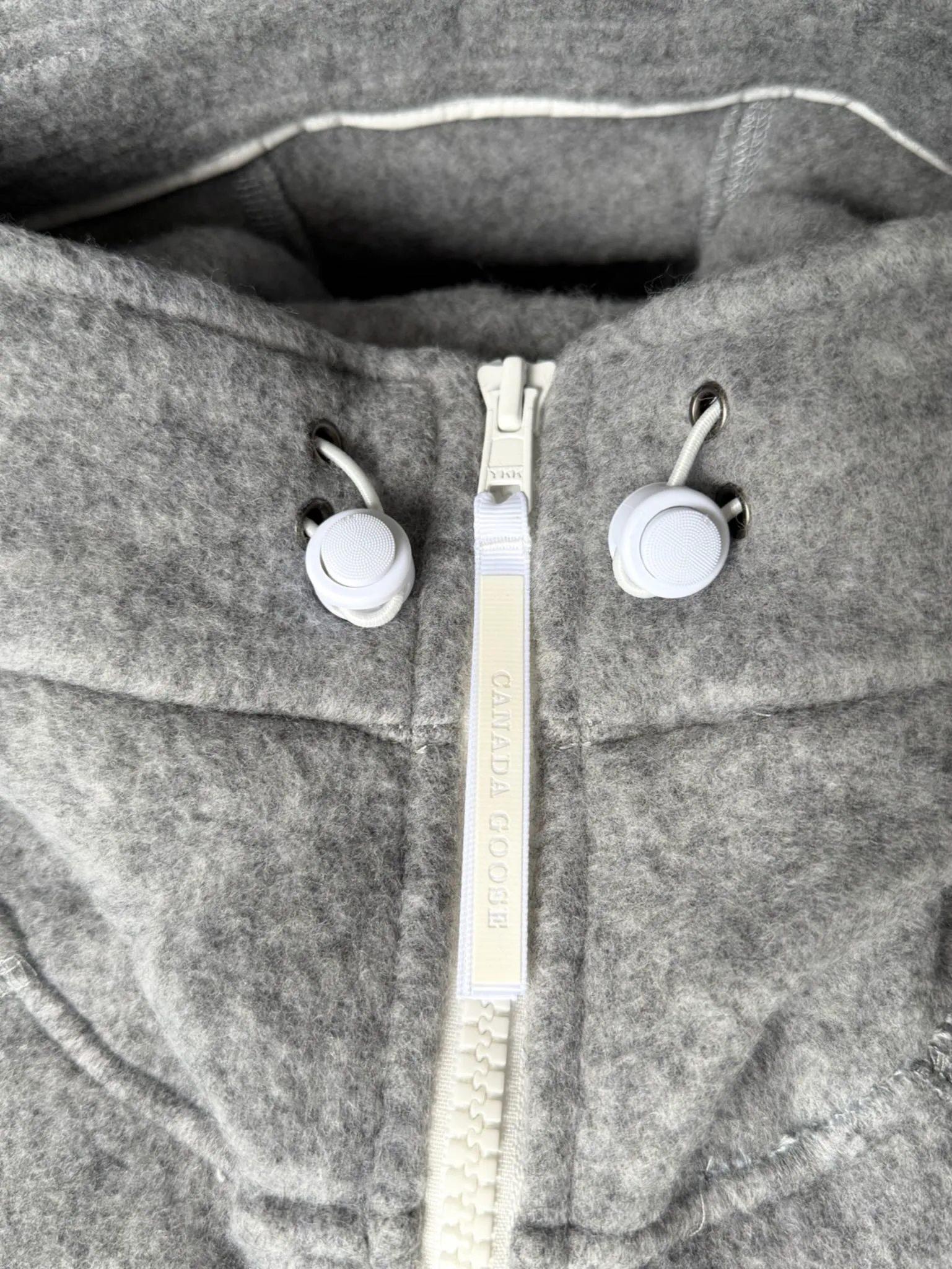 P660 Canada Goose Fleece Wool Badge Hooded Jacket Fabric selection: Wool fleece fabric blended with wool as the main body and a very small amount of spandex and polyester fiber. Wool is a core natural ingredient that provides unparalleled temperature regulation, antibacterial and anti-odor properties and a skin-friendly feel. The feeding of a small amount of spandex gives the fabric a certain degree of four-way elasticity, making it non-restrictive during daily activities. As the basis of fleece's structure, polyester fiber enhances the fabric's durability, wrinkle resistance and quick-drying properties. It contributes to the loft of the fleece and provides functions such as trapping air.  Detail 1: The sleeves and hem are closed with 2×2 ribbing. Its strong elasticity can closely fit wrists and waists of different thicknesses, forming an effective 'seal' to prevent cold wind from blowing back. It can still maintain its original shape after repeated stretching and use, and is not easy to loose and deform. And the ribbed cuffs can convey a sense of design and enhance the visual beauty.  Detail 2: The combination of hood design and elastic buckle improves warmth and windproof performance when wearing. Accessories: Customized elastic drawstring, elastic buckle, custom zipper pendant, custom armband Size: S M L Color: black gray coffee rice pink